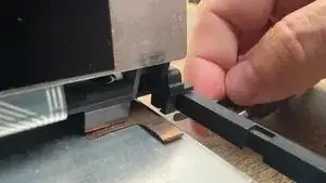 Open the keyboard fully and locate two clips holding the rear keyboard cover on. They will be located at the pivot point.