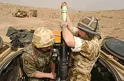 Two soldiers with a mortar gun—one loading and the other aiming