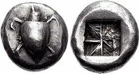 Both sides of a silver coin. One side has a relief of a turtle; the other the impression of a square divided into eight segments.
