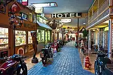 Indoor pedestrian street with almost lifestyle storefronts, flanked by motorbikes.
