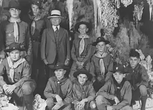 Photograph of Burnham in 1941 celebrating his 80th birthday with several Boy Scouts. All of them are posing in Carlsbad caverns. The boys are dressed in their Boy Scout uniforms. Burnham is dressed in a full suit and tie and wearing a white hat.