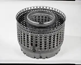J85 annular combustor, displayed rear-end up. When installed in the engine this open end is closed by the first stage turbine nozzle vane ring the flow area of which (together with the area of the exhaust nozzle) back pressures the compressor to control its pressure rise and flow rate as shown on a compressor map.