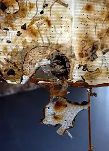 The installation "Les partitions de vent" (detail), 2013. Burned sheet music drawn upon, resin, found object (music stand)