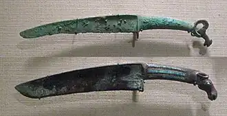 Shang dynasty curved bronze knives with turquoise inlays and animal pommel.