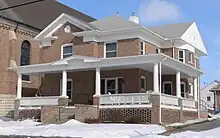Two-story brick building with wrap-around porch