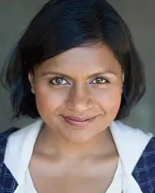 A close-up of Mindy Kaling's face. Kaling smiles into the camera. Her hair is shorter than shoulder-length; it is parted on the left, and swept back behind her right ear.