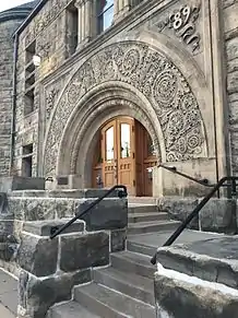 Big wooden doors under a large stone arch. The front entrance of the Mabel Tainter Center of the Arts.